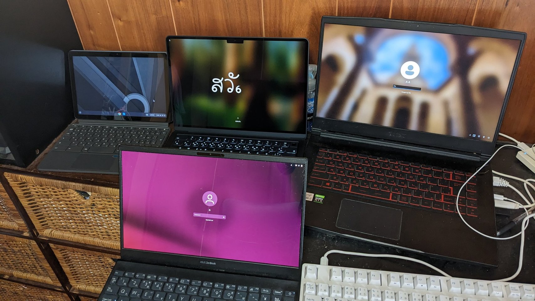 A desk with multiple laptops running Windows, Linux, and macOS